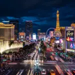 The Las Vegas strip at night with glowing neon signs and luxury club facades.